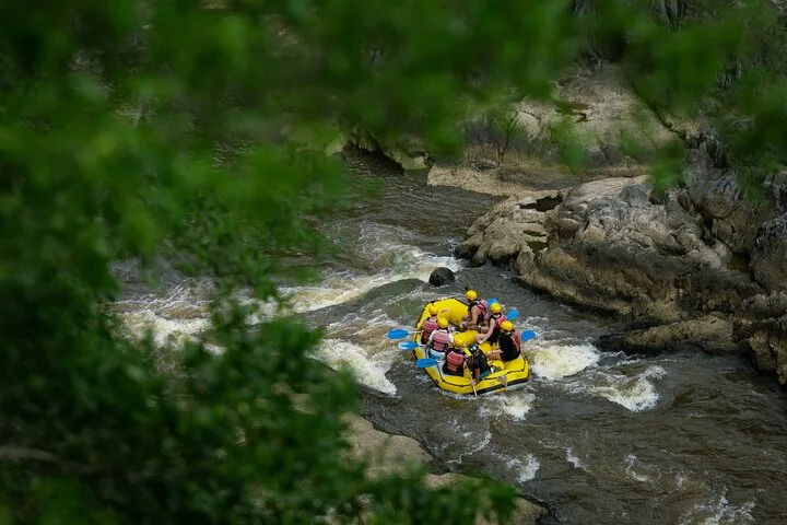 View from above of a yellow raft navigating river rapids surrounded by rocks.